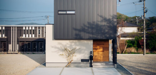 陰影が映える、凛とした佇まい。 黒ガルバリウムと塗り壁のコントラストが美しい、シンプルかつ力強いフォルムの住まい。 春には、桜の影がやわらかく壁に揺れ、優しい季節の表情を添えます。